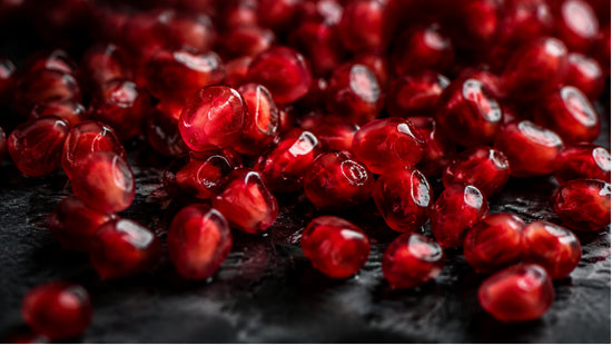 Close-up abstract photograph of glossy pomegranate seeds with dramatic lighting, symbolizing the hormonal and metabolic connection in PCOS.