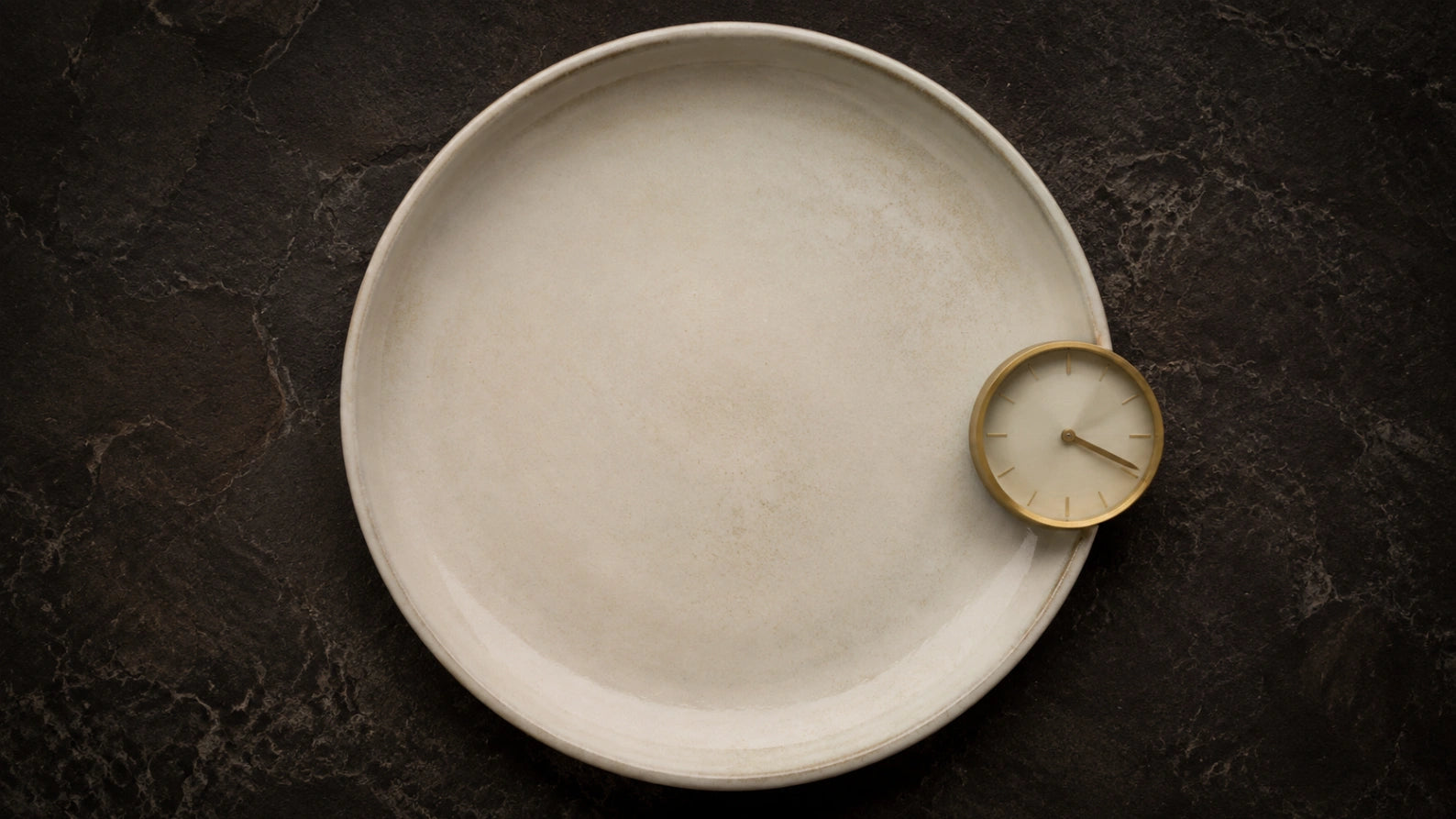 Top-down abstract photograph of an empty plate with a clock, representing the importance of timing when taking berberine before or after meals.